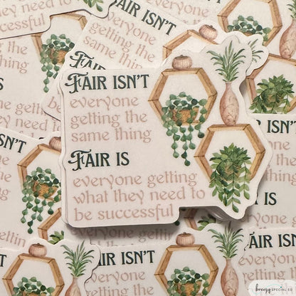 A sticker with a quote about fairness, featuring a design with plants and decorative elements in green tones.