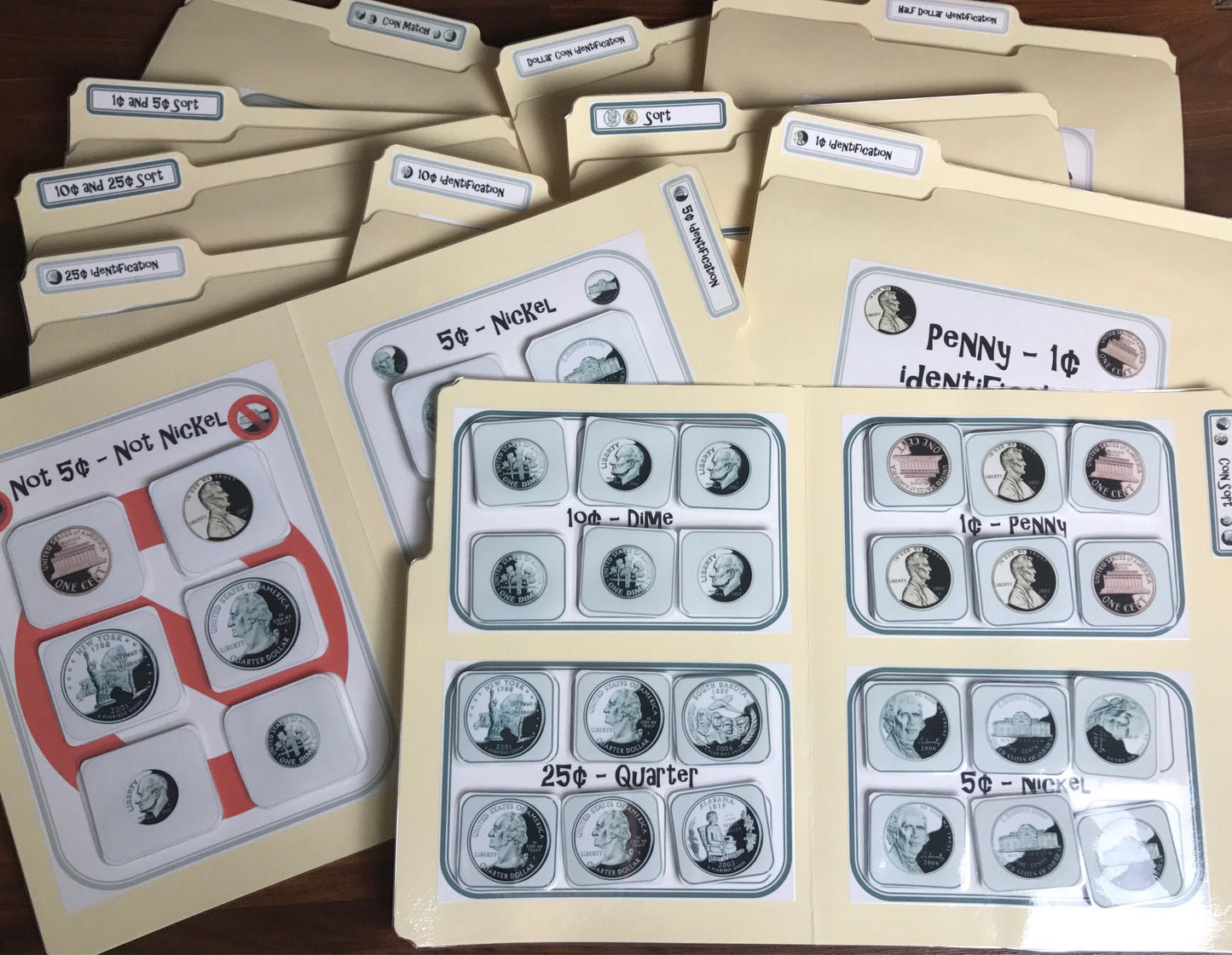 Set of light gray file folders with labeled flaps, featuring cut-outs of US coin images for special educational purposes.