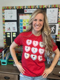 Teacher in front of bulletin board wearing a candy heart Valentine's Day tshirt with symbol cards (PCS) inside them